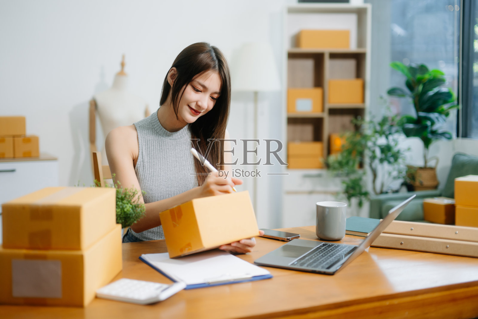 在家办公室工作的女性小企业创业者，使用盒子、平板电脑和笔记本电脑进行在线营销。照片摄影图片