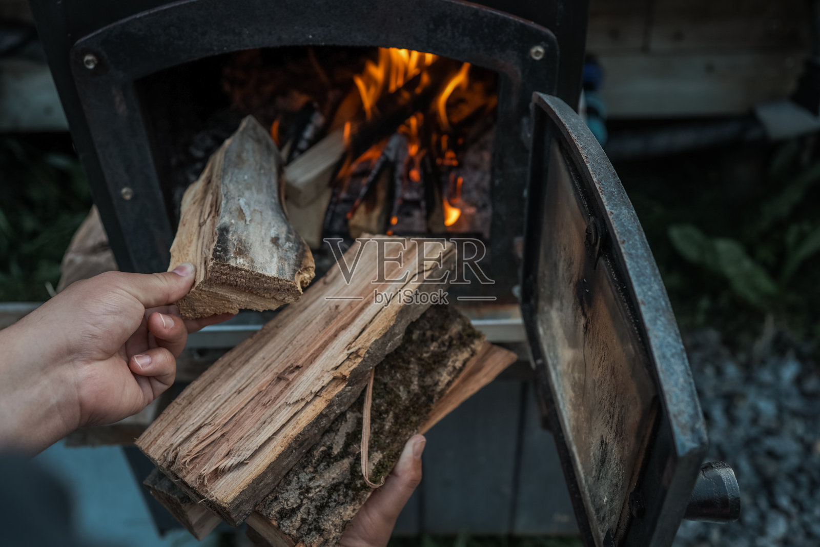 黑色金属炉内燃烧的木柴特写，明亮的橙色火焰和闪烁的余烬，营造出温暖而质朴的氛围照片摄影图片