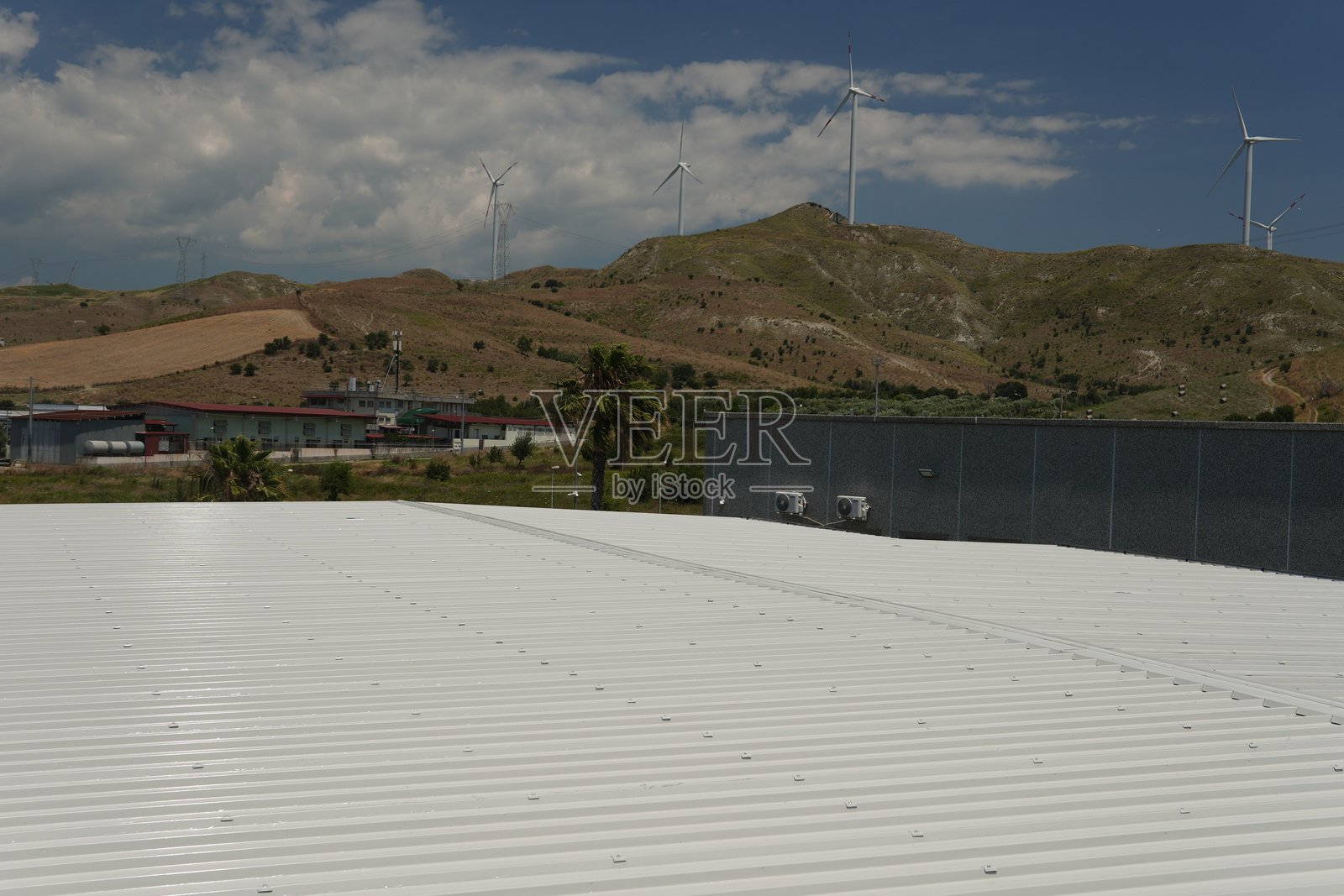 工业屋顶配有白色夹心板。屋脊盖用铆钉和密封剂固定，以确保强度和防水性。照片摄影图片