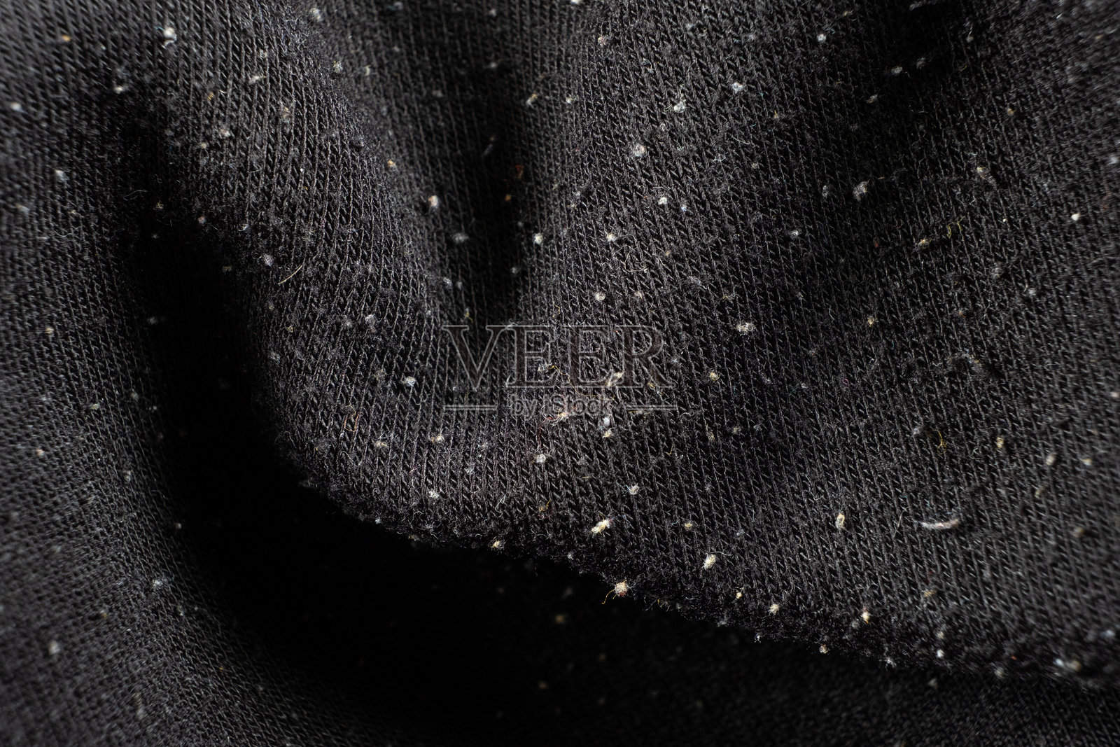 黑色织物的宏观纹理，表面有大量起球和损伤。照片摄影图片