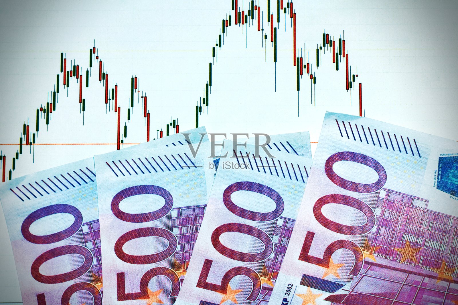 一只手握着500欧元纸币，背景是显示股票增长图表的监视器。抽象的金融成功。照片摄影图片