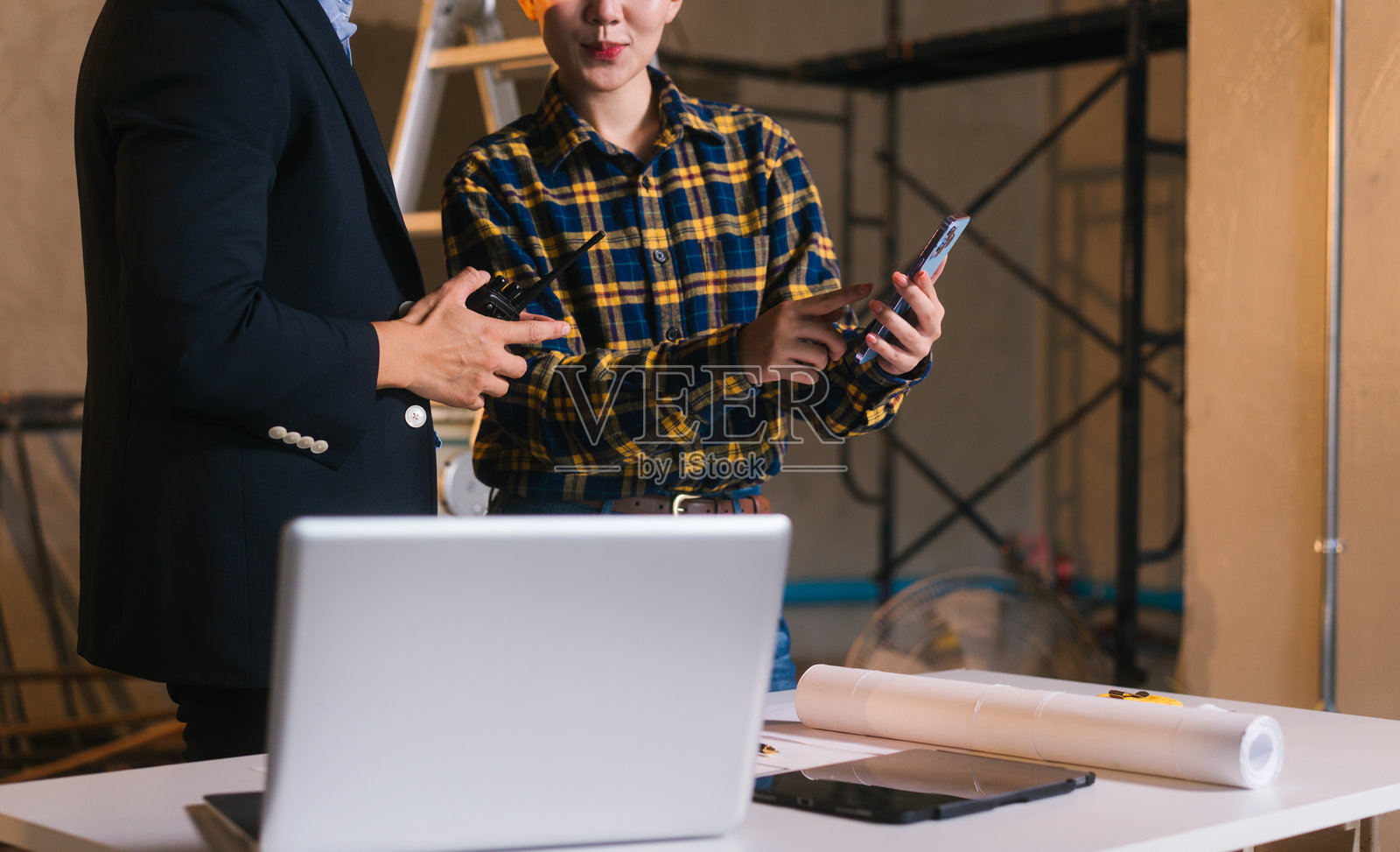 亚洲男女工程师正在检查建筑蓝图，并审查钢材和石灰石的材料成本，为建筑项目准备竞争性投标提案，与项目团队合作。照片摄影图片