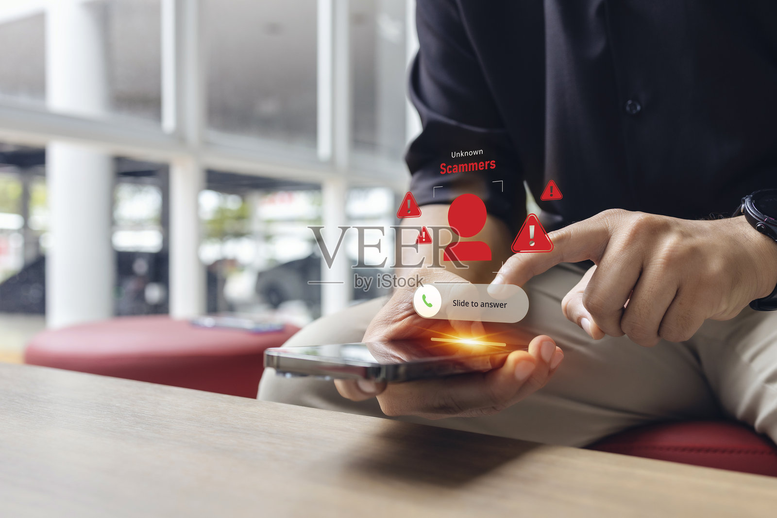 男子在办公室环境中接听诈骗电话，智能手机屏幕上显示网络威胁警报图标照片摄影图片