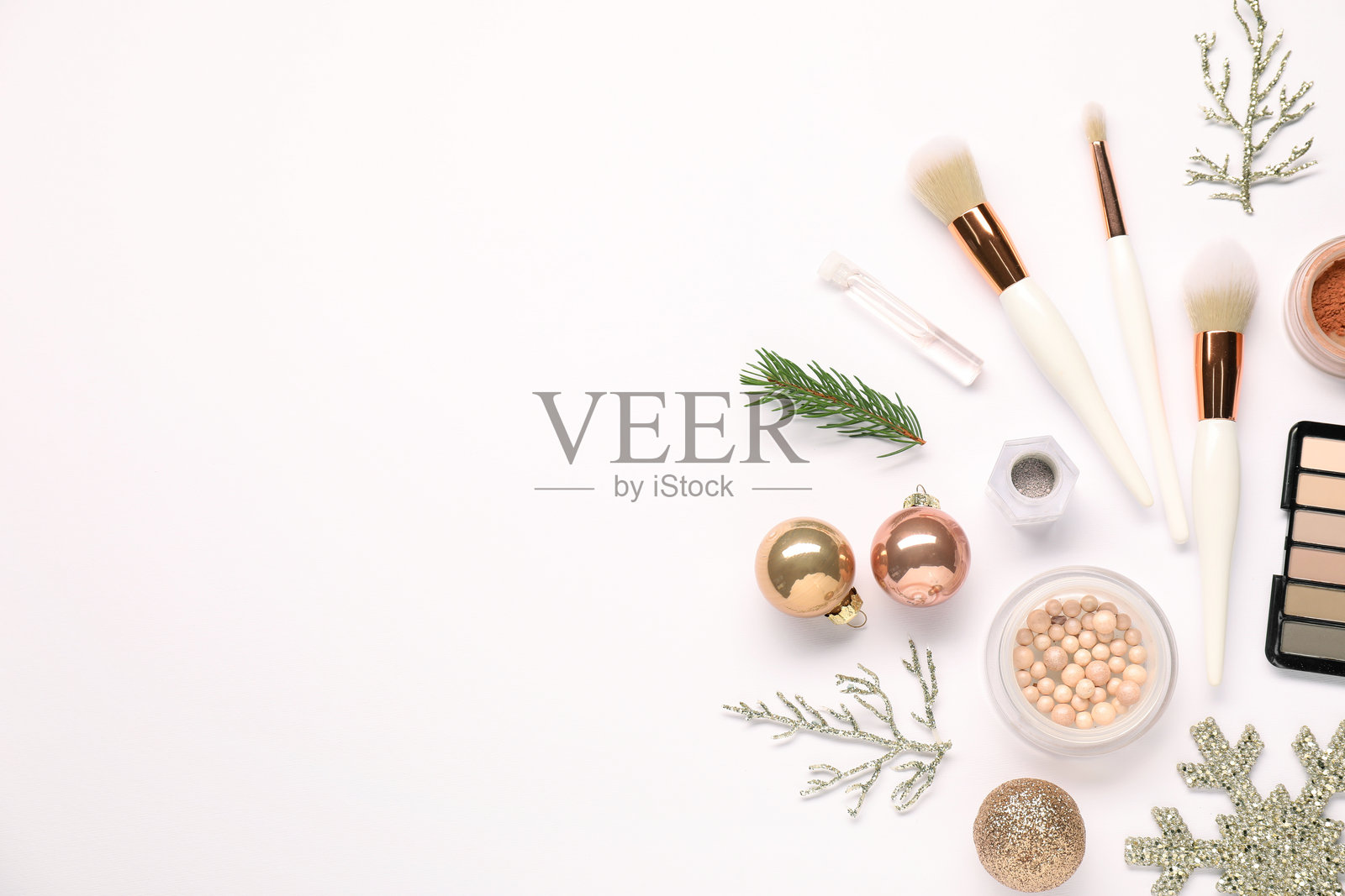 不同的化妆刷、装饰性化妆品和圣诞装饰品在白色背景上的平铺。留有文本空间。照片摄影图片