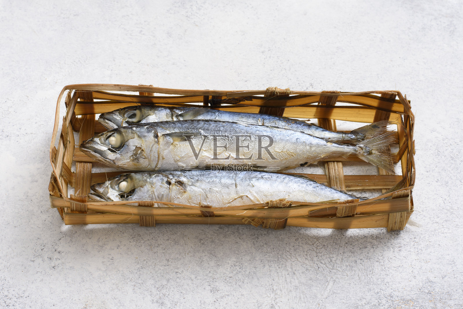 竹篮中的印尼传统新鲜盐鱼，摆放在白色桌子上照片摄影图片