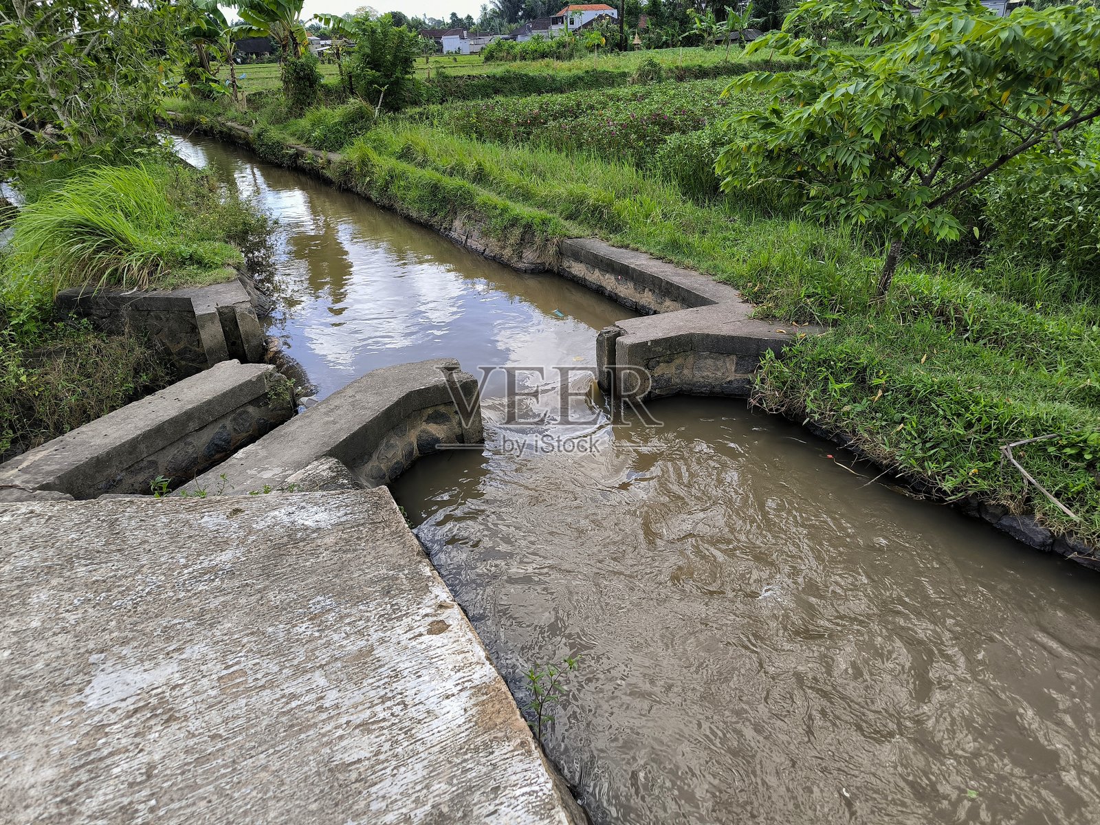 巴厘岛灌溉系统将新鲜水源分配到梯田稻田，对季节性农业至关重要。传统的灌溉渠流经印度尼西亚巴厘岛的稻田——这是古老的苏巴克系统的一部分。照片摄影图片