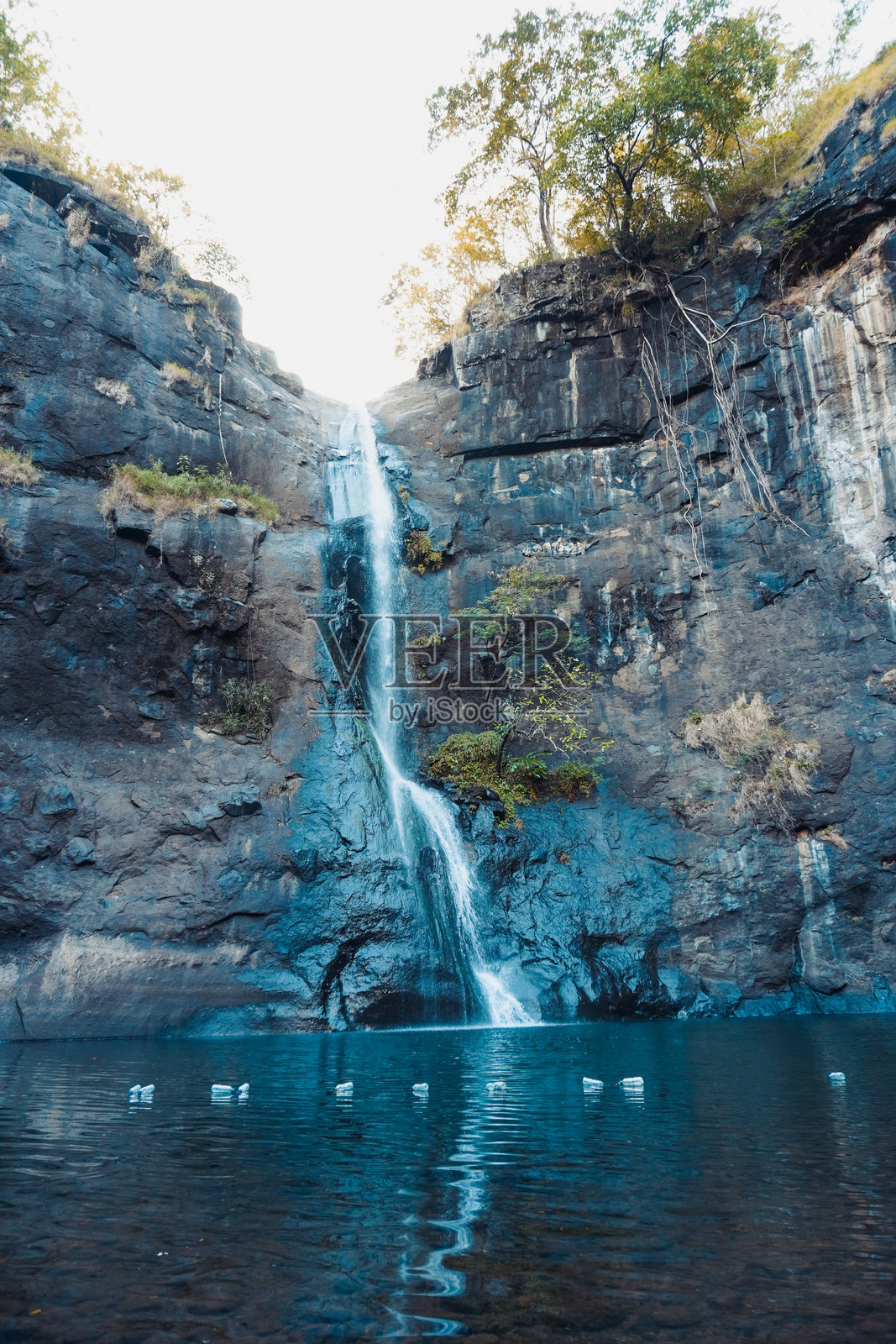 瀑布从岩石形成中倾泻而下，映照在宁静的湖面上照片摄影图片