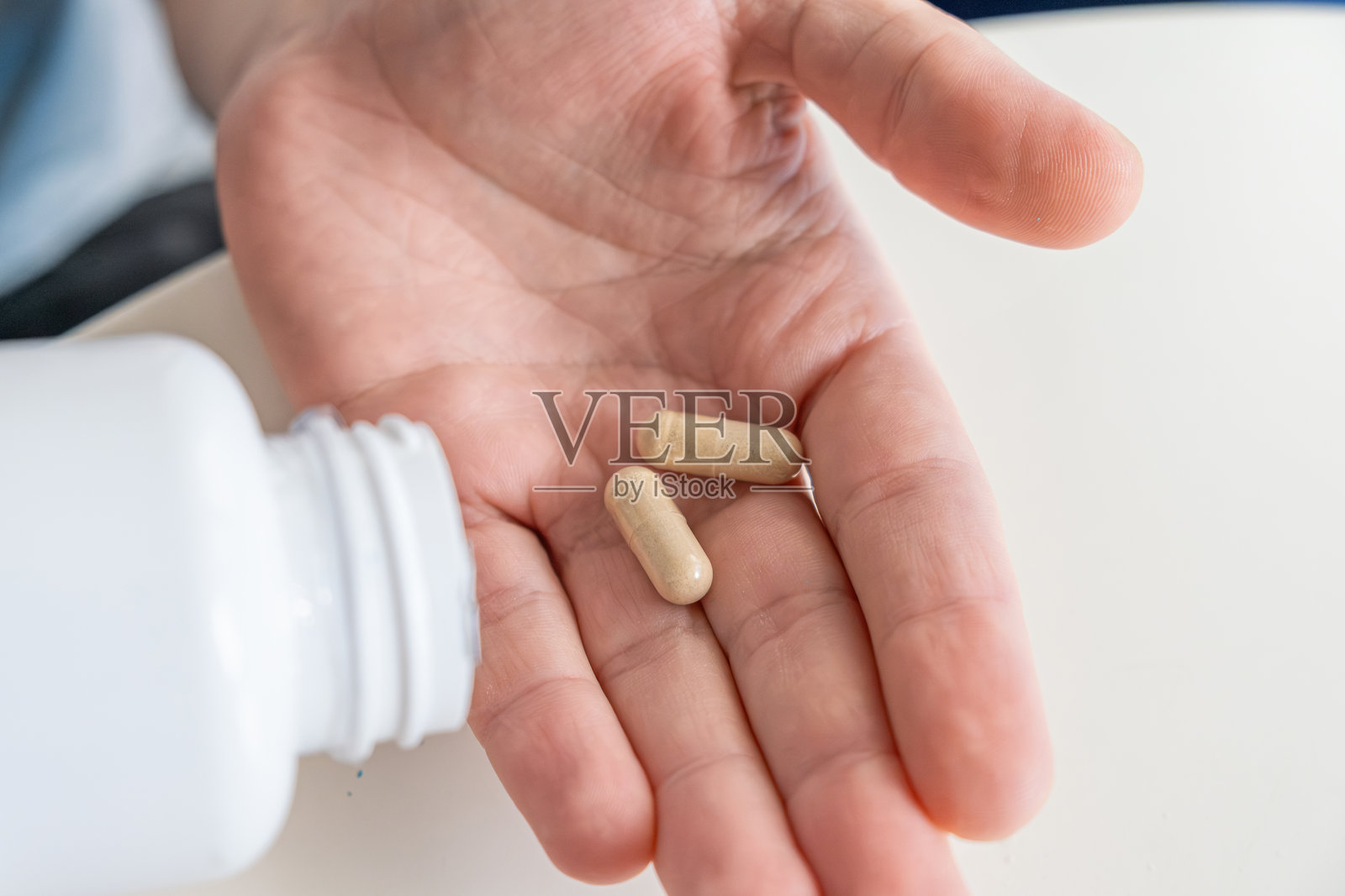 男子从药瓶中倒出米色益生菌胶囊到手中。营养补充剂。肠道健康、日常保健、消化支持、免疫系统增强和微生物群平衡。照片摄影图片