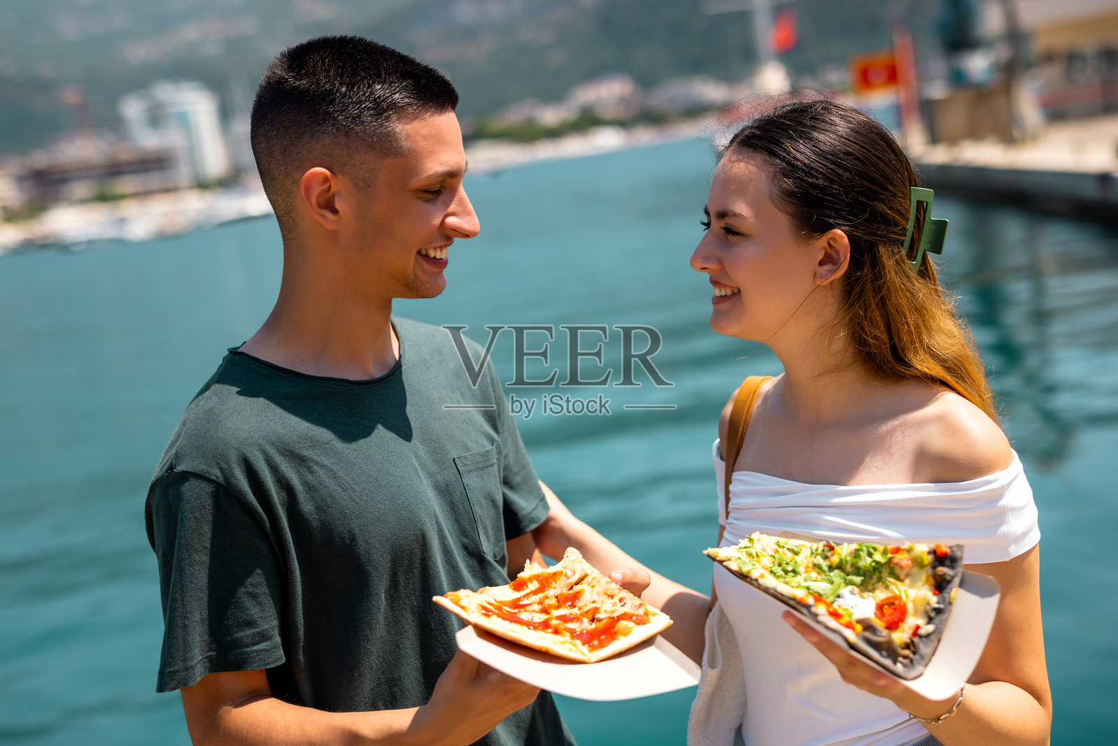 情侣在海边度假时吃披萨并交谈照片摄影图片