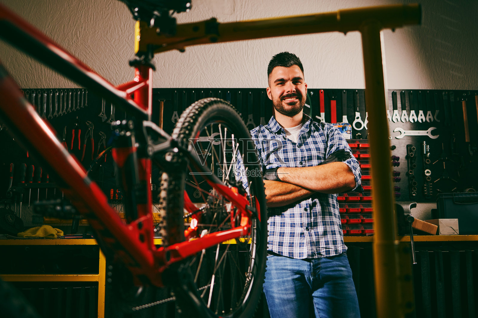 微笑的机械师在自行车修理店里双臂交叉照片摄影图片