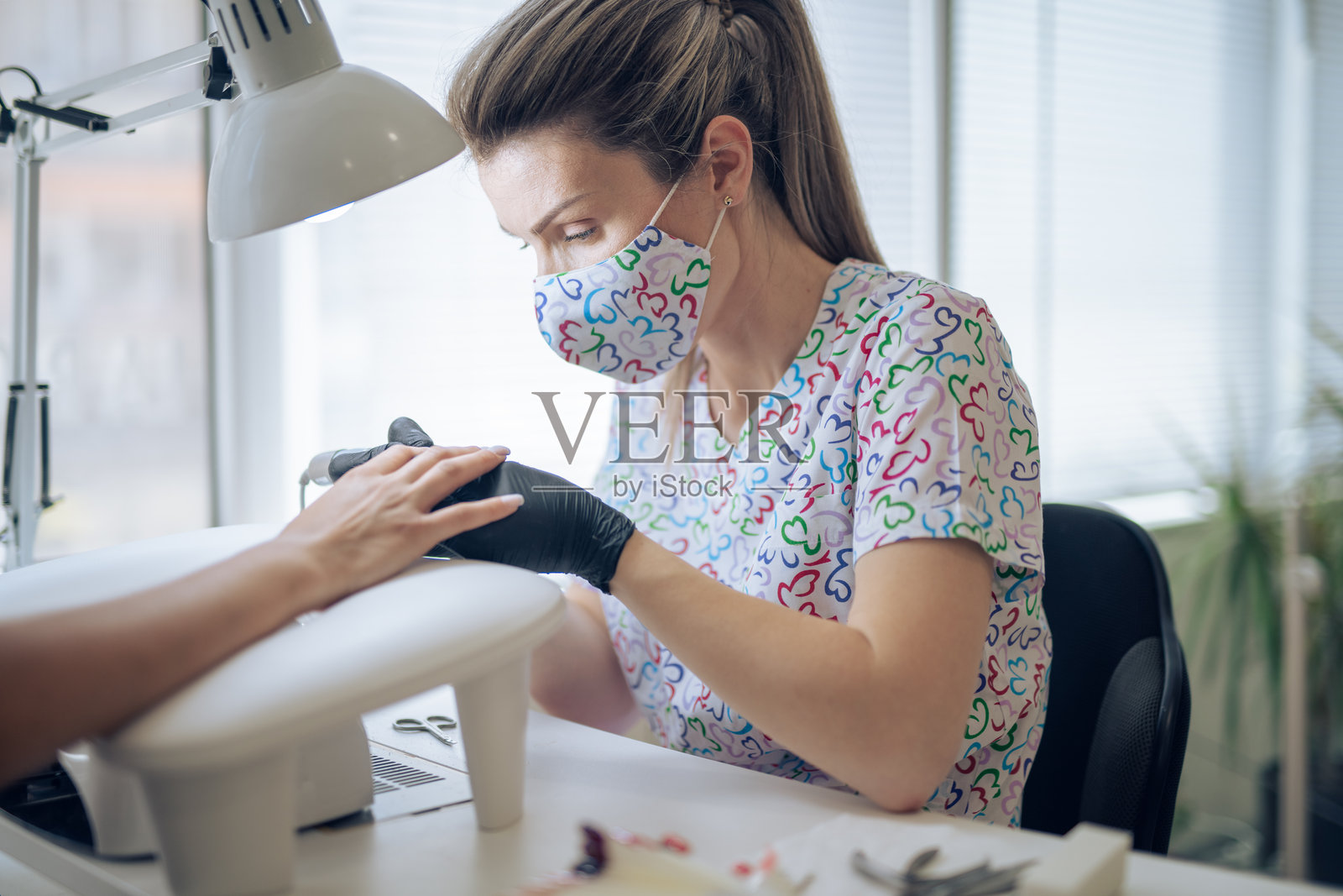 专业美甲师在美容院为客户做美甲。照片摄影图片