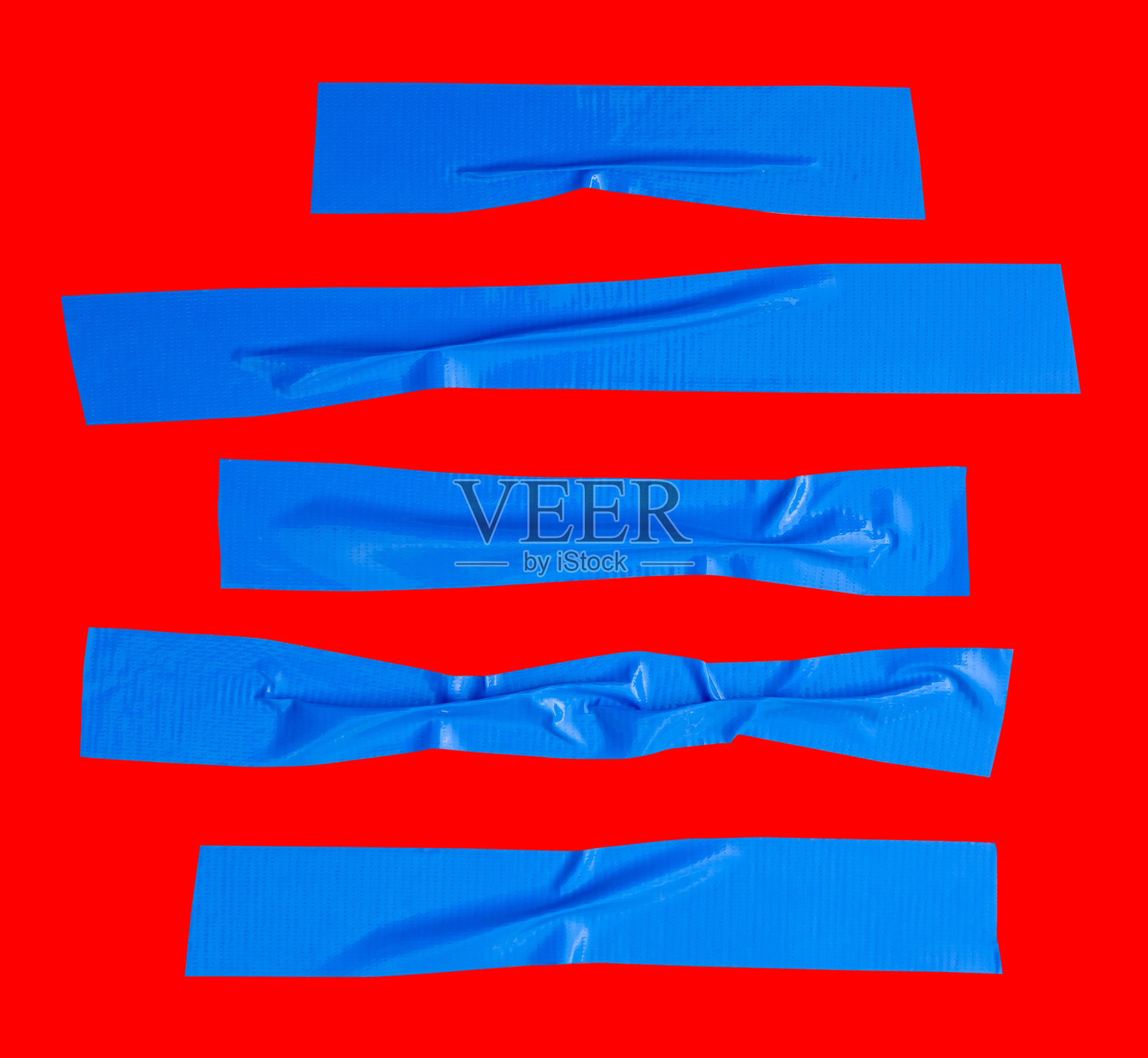 从上方看一组皱褶或揉皱的蓝色粘性乙烯基胶带或布带，呈条纹状，孤立在红色背景上，带有抠图路径。照片摄影图片