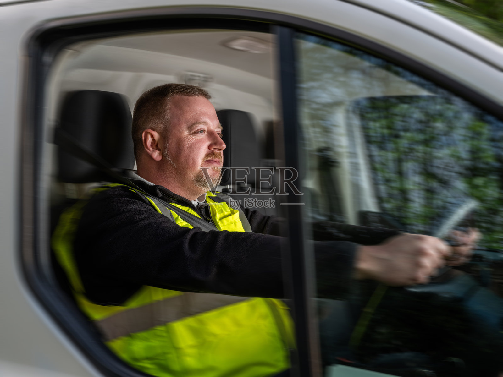 穿着高可视性背心的货车司机在行驶中照片摄影图片