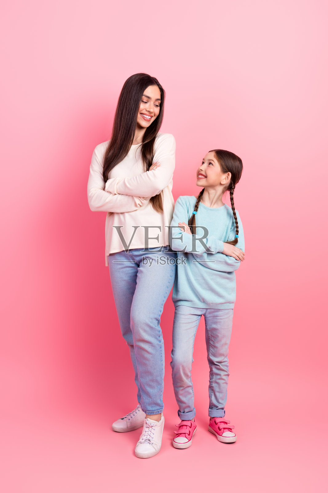 快乐的母女在鲜艳的粉色背景前共享快乐时光。照片摄影图片