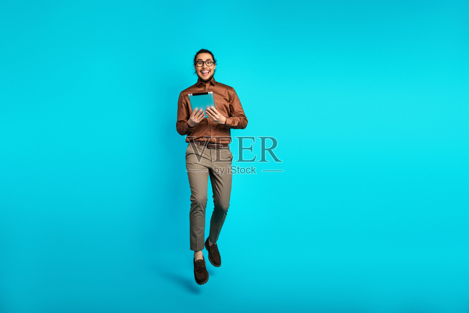 专业年轻男士手持平板，背景为生动的青绿色，展现出时尚与商业自信。照片摄影图片