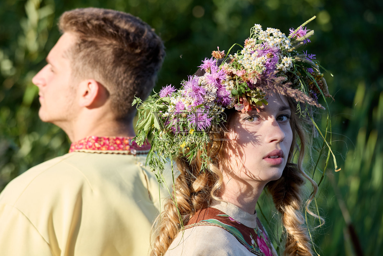 美丽的年轻女性戴着花冠，背对背与她的男朋友站在一起，肖像。照片摄影图片