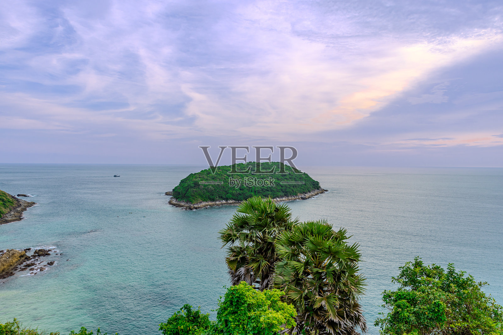 普罗姆提普角的日落，俯瞰奈汉海滩，海岸附近有一个小岛科曼岛，位于泰国普吉岛。郁郁葱葱的绿色树木和安达曼海的碧蓝海水。照片摄影图片