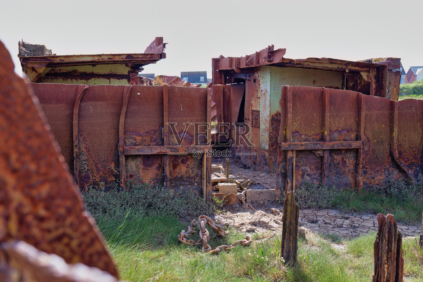 一座生锈、腐朽的建筑物在草地上被遗弃。照片摄影图片