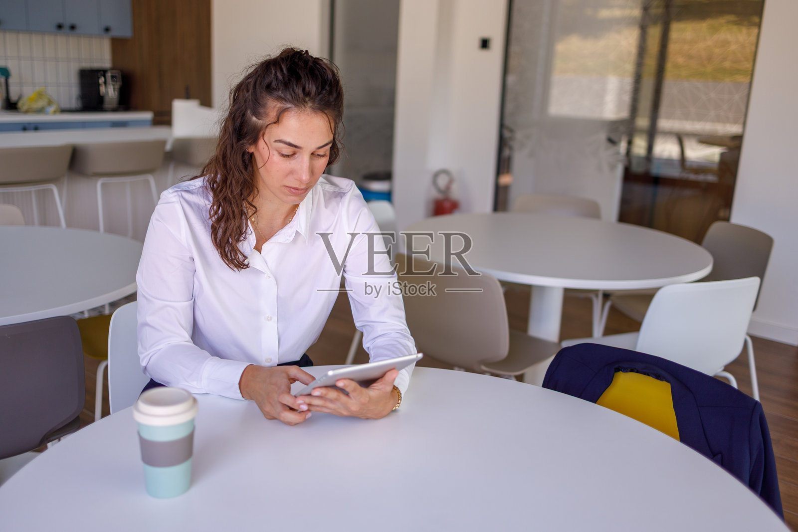 年轻女商人在现代办公室餐厅休息时使用数字平板电脑照片摄影图片