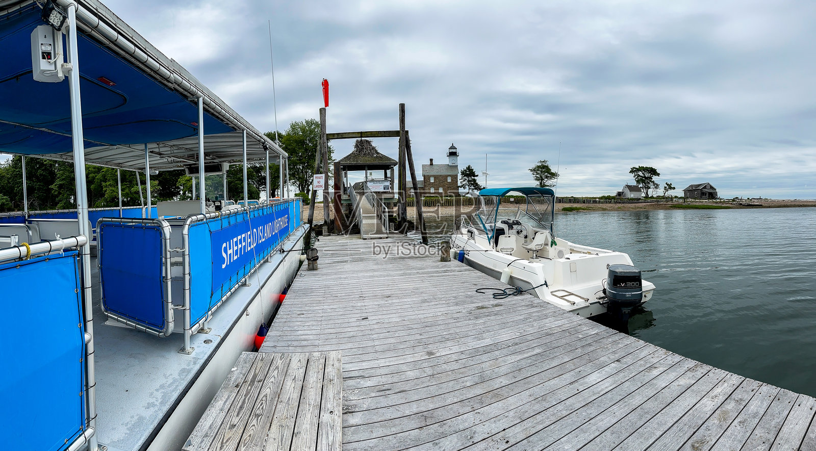 远处的谢菲尔德岛灯塔,停靠的船只和云彩照片摄影图片