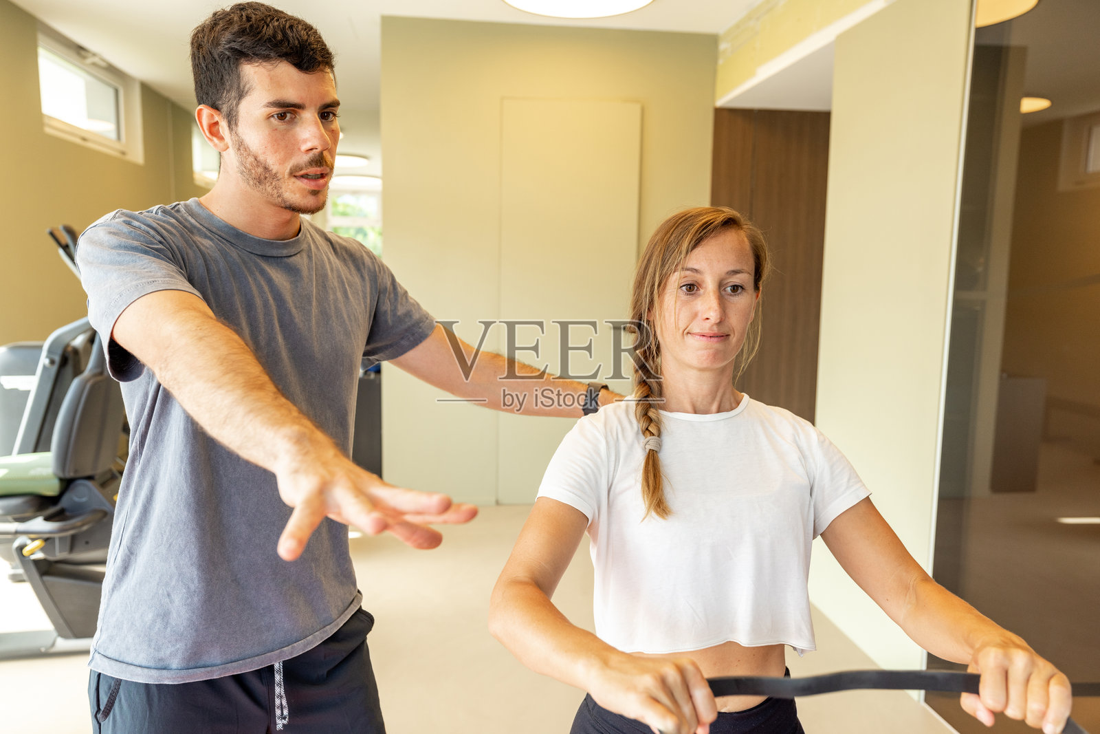 私人教练在健身房协助女性进行抗阻训练照片摄影图片