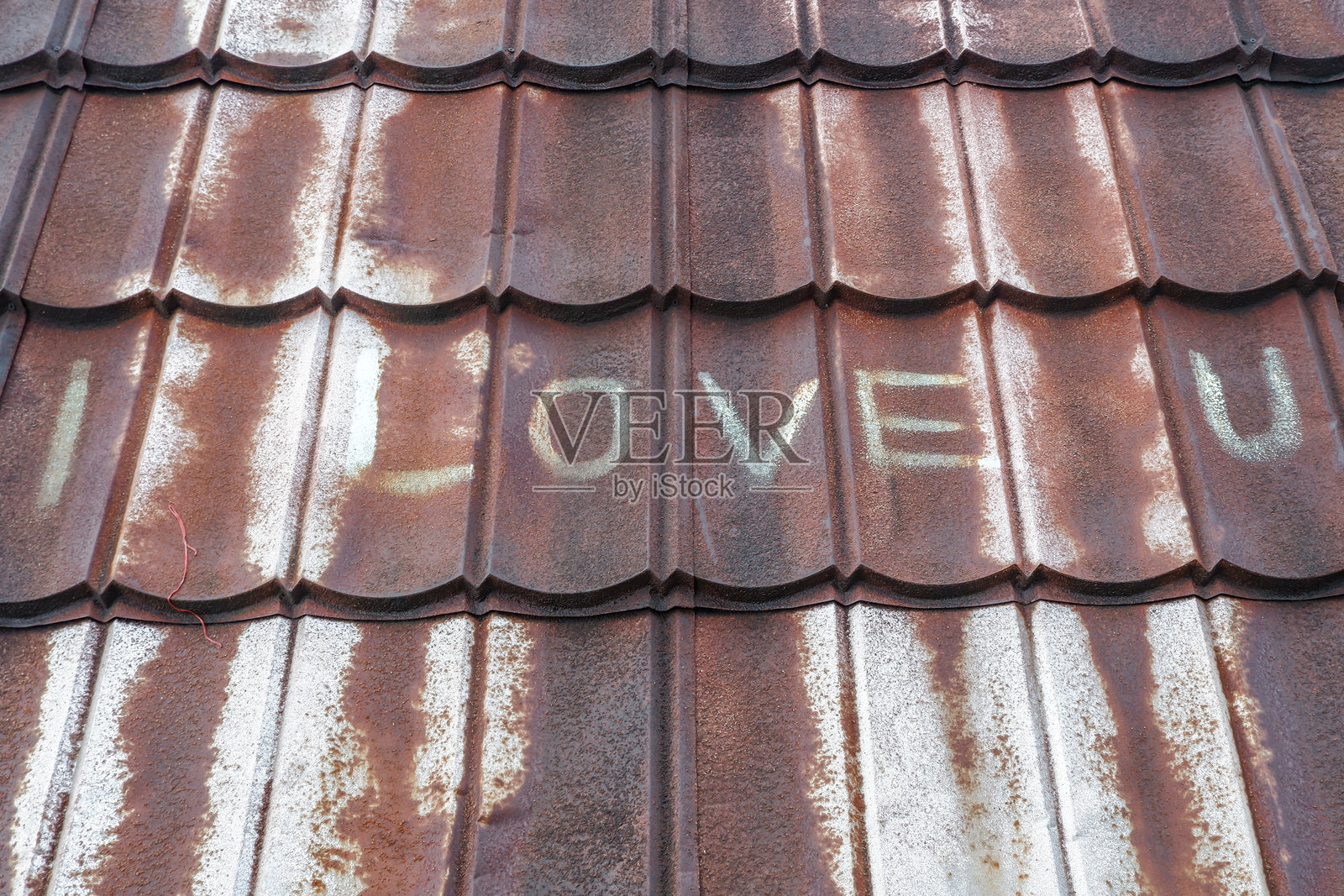 “我爱你”这几个字写在生锈的轻钢屋顶上。照片摄影图片