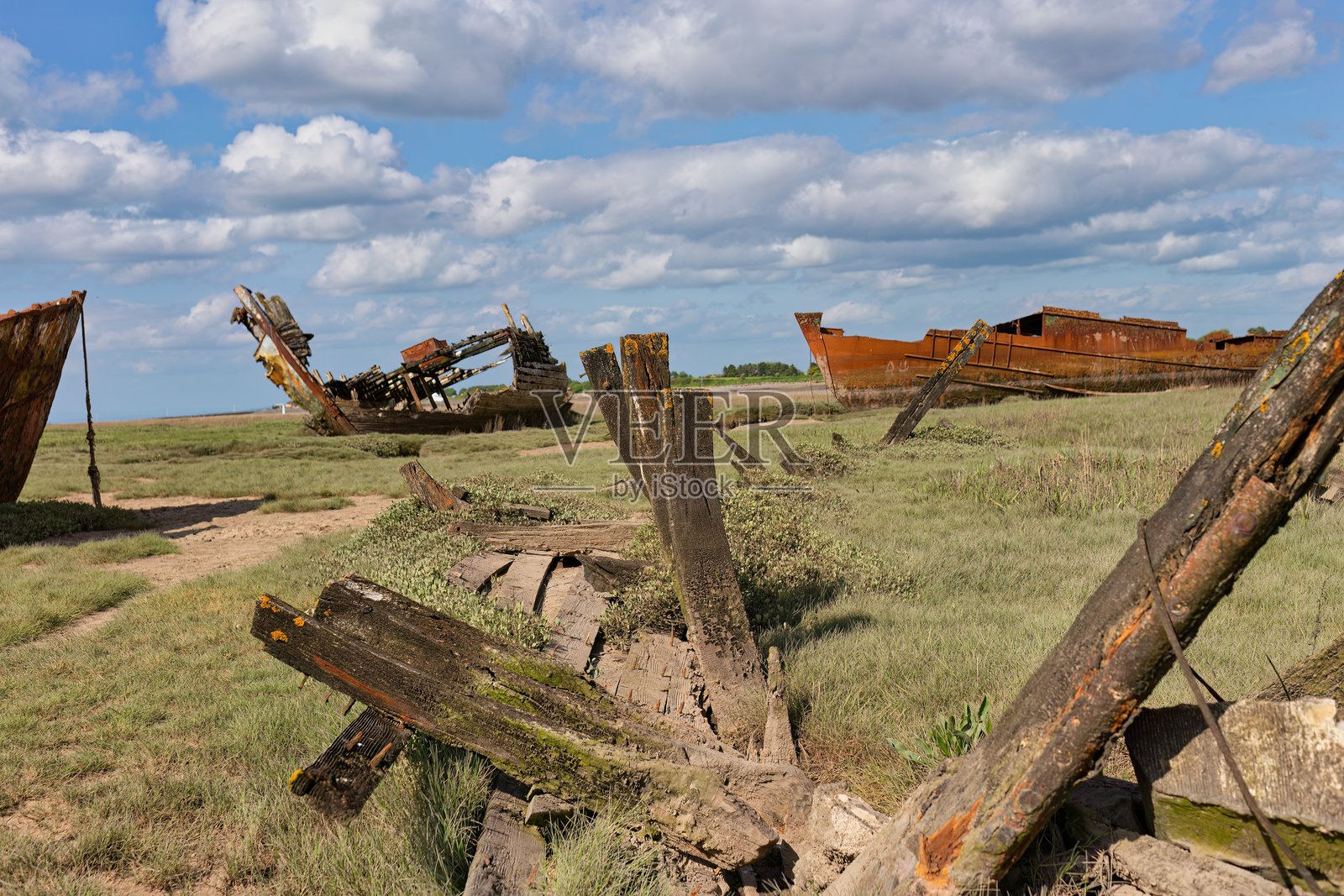 破旧的船只静静地停在草地上，天空布满了乌云。照片摄影图片