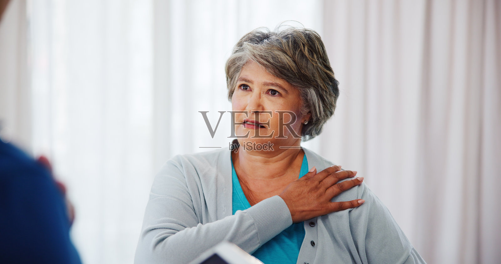 成熟的女性，肩部疼痛或在诊所咨询物理治疗师以治疗伤害或肌肉紧张。女性，手臂酸痛或不适，接受物理治疗以进行检查、医疗诊断或建议。照片摄影图片