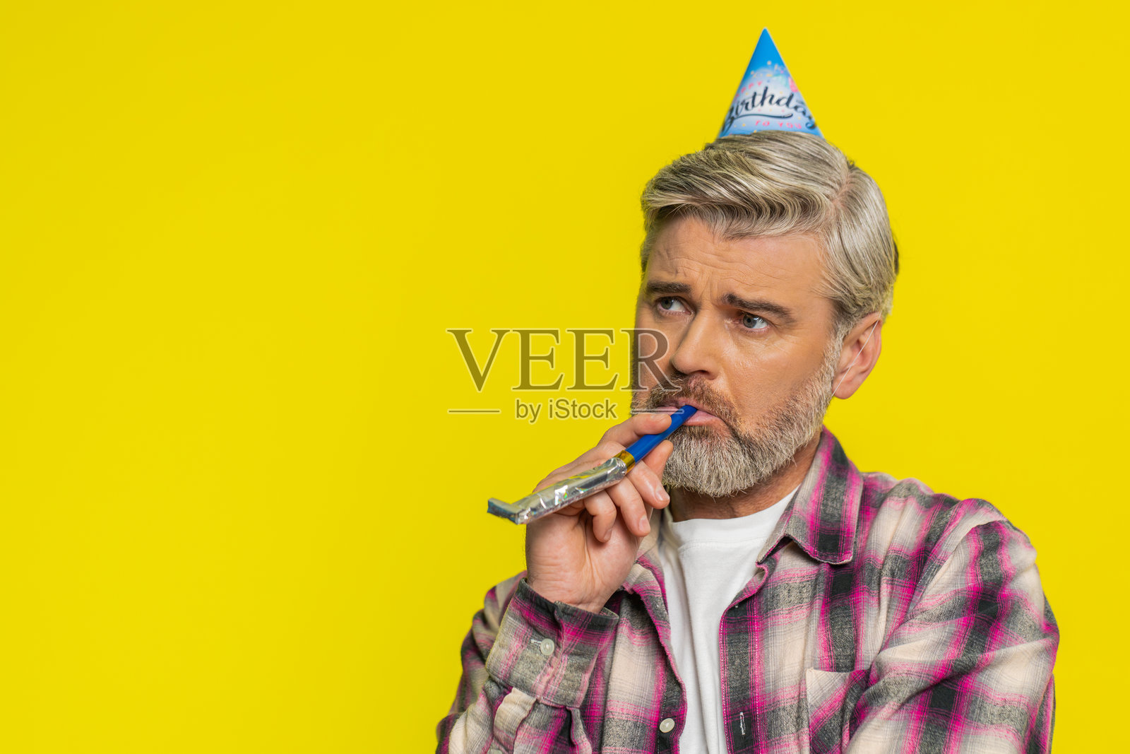 成熟男人孤独的生日派对，戴着尖顶帽，吹着喇叭，心情无聊，孤独的庆祝，感到沮丧和疲惫。照片摄影图片