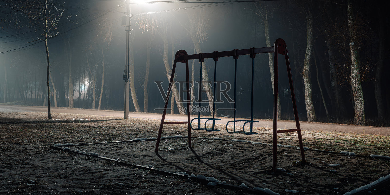 夜晚空荡荡的儿童游乐场，柔和的街灯照亮着四周。照片摄影图片