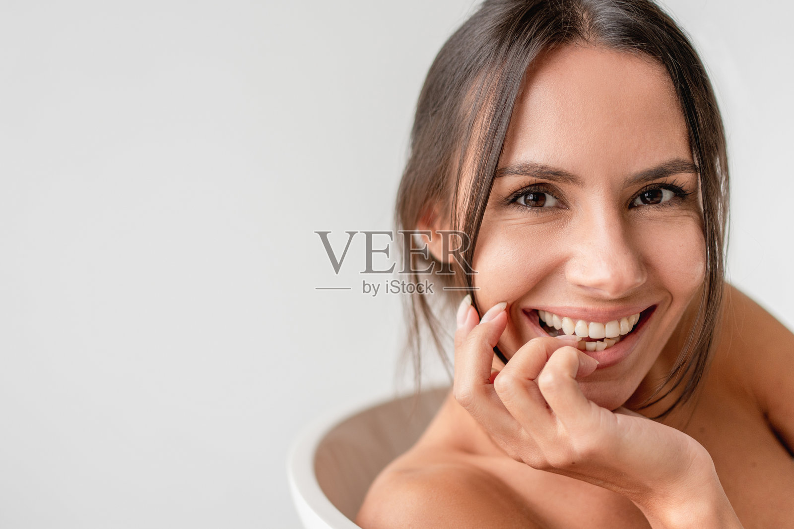 美丽女性在浴缸中泡澡，微笑着看向镜头，享受泡沫，放松身心，浴室内的沐浴美容产品概念，留白空间。照片摄影图片