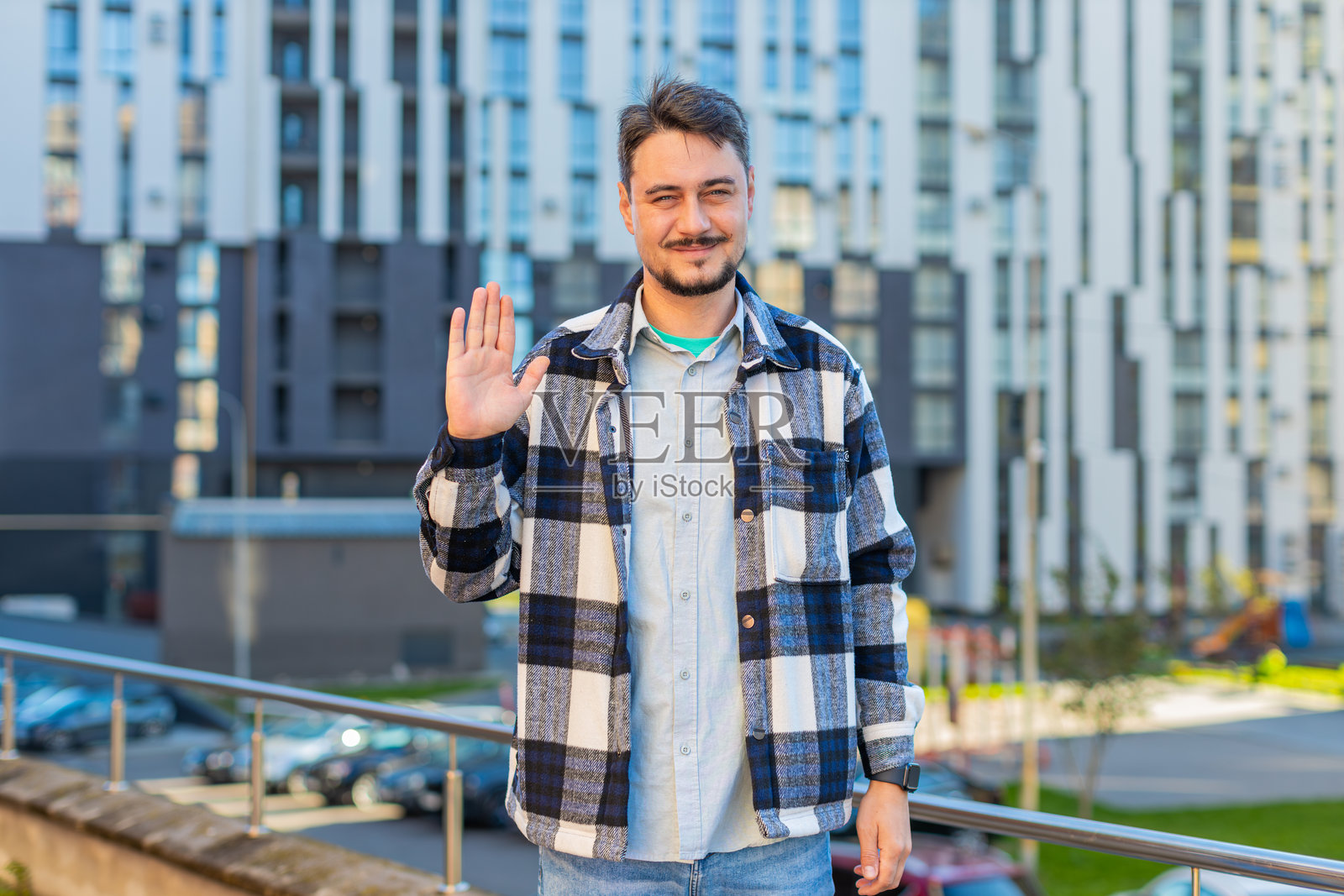 愉快的成熟男性游客在城市街道上微笑着对着镜头挥手问好。照片摄影图片