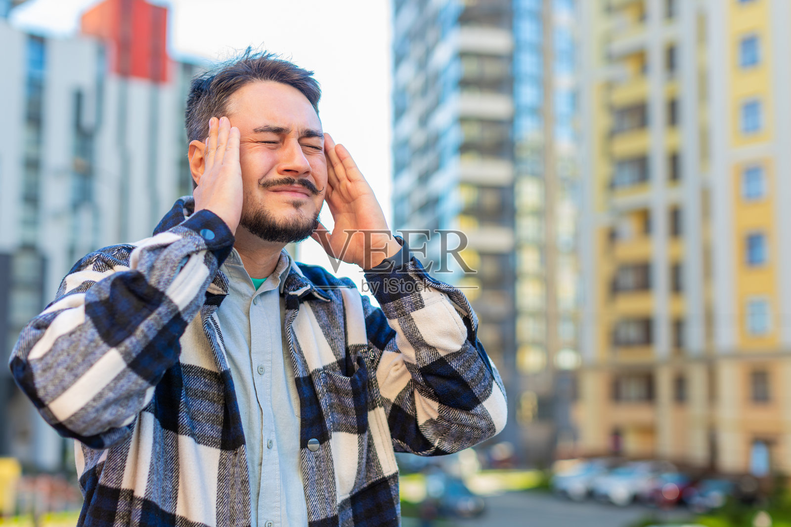 生病的成熟白人商人在城市街道上靠着建筑物感到头痛照片摄影图片
