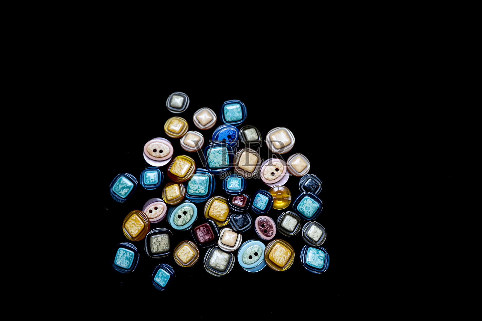 五颜六色的裙子纽扣，底孔和顶孔，黑色背景上的五颜六色裙子纽扣照片摄影图片