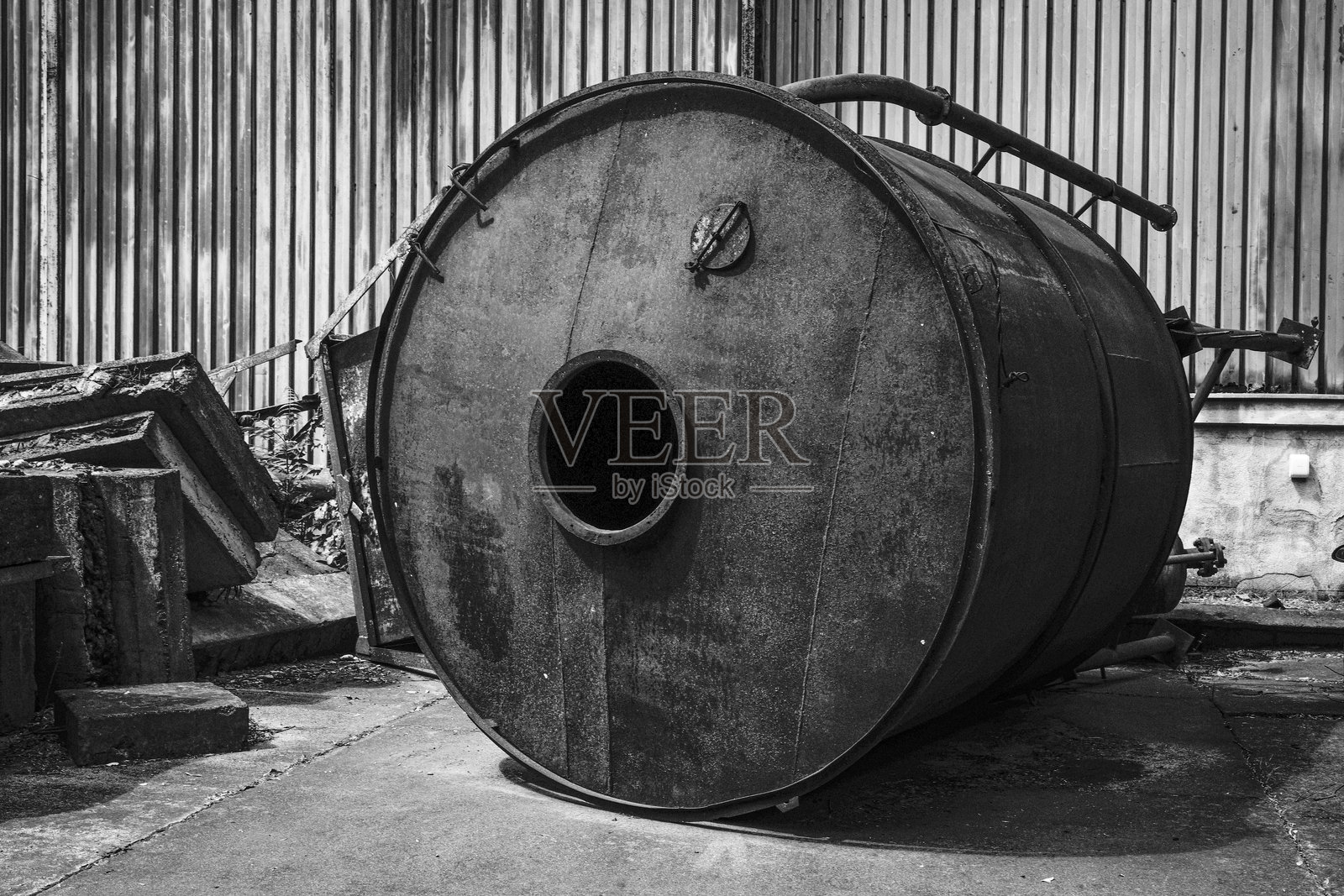 生锈的金属圆柱靠在波纹金属墙上照片摄影图片