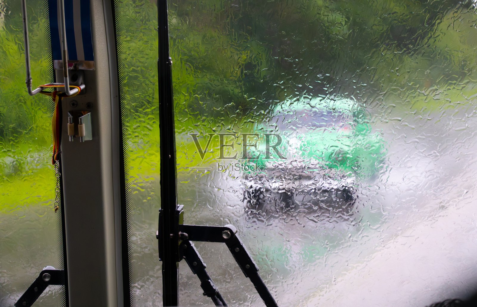 大雨，湿润的挡风玻璃后面可见古巴的一辆绿色美国车，雨刷正在工作。照片摄影图片