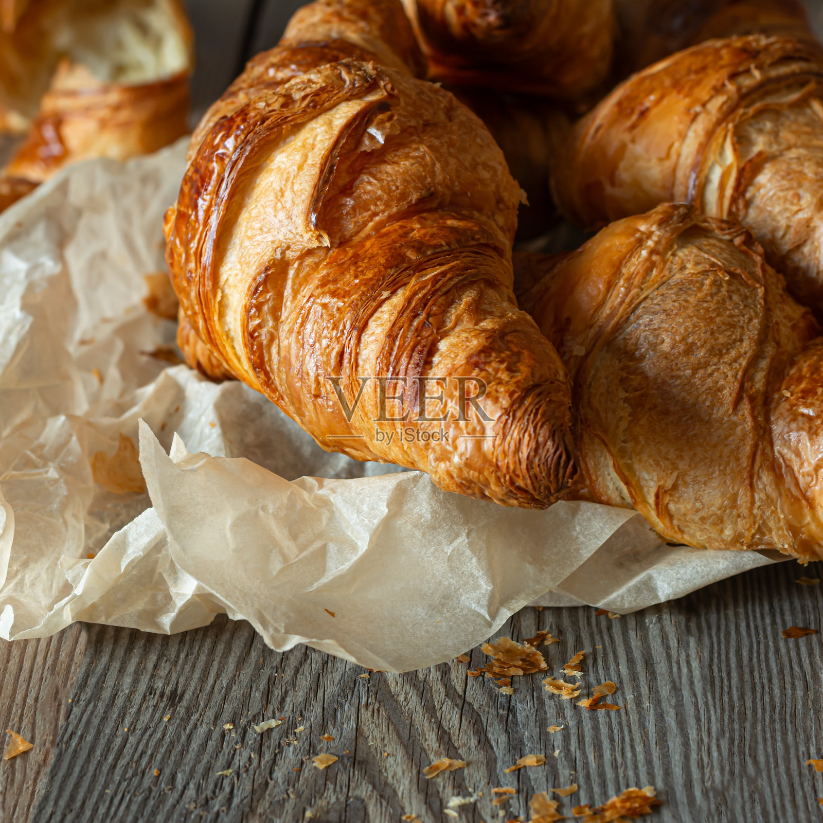 木质背景上新鲜酥脆的法式羊角面包。传统的红扑扑的糕点(包子)是早餐，美味的甜点。照片摄影图片