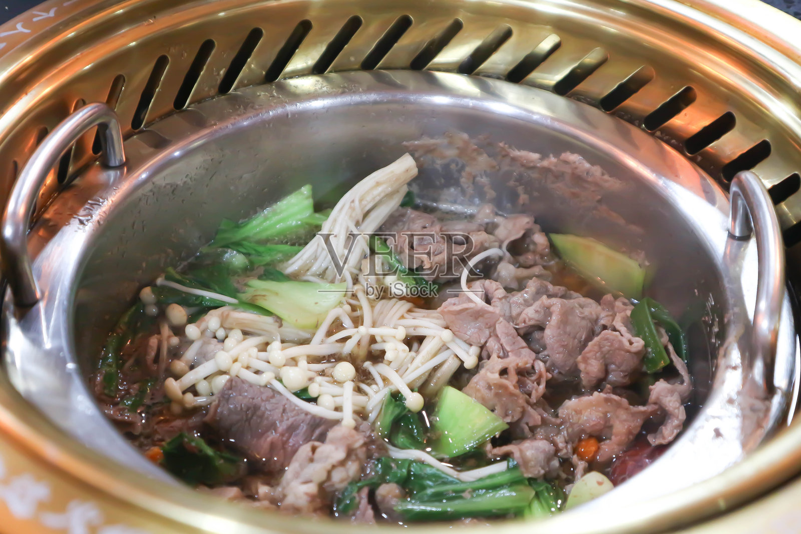 寿喜烧、涮锅或火锅，锅中有切片牛肉或蔬菜汤。照片摄影图片