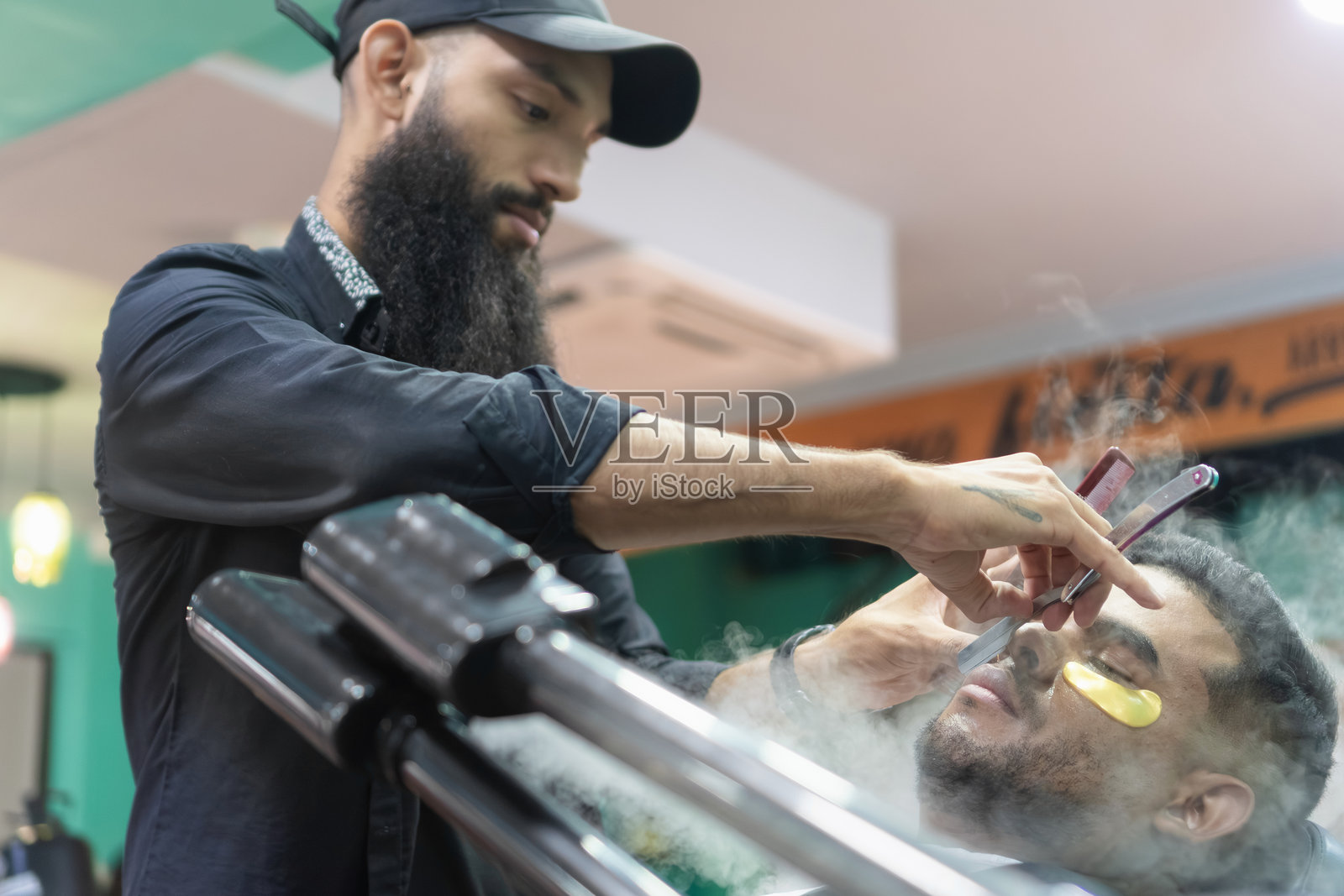 理发师在美容院用剃刀为顾客刮胡子照片摄影图片