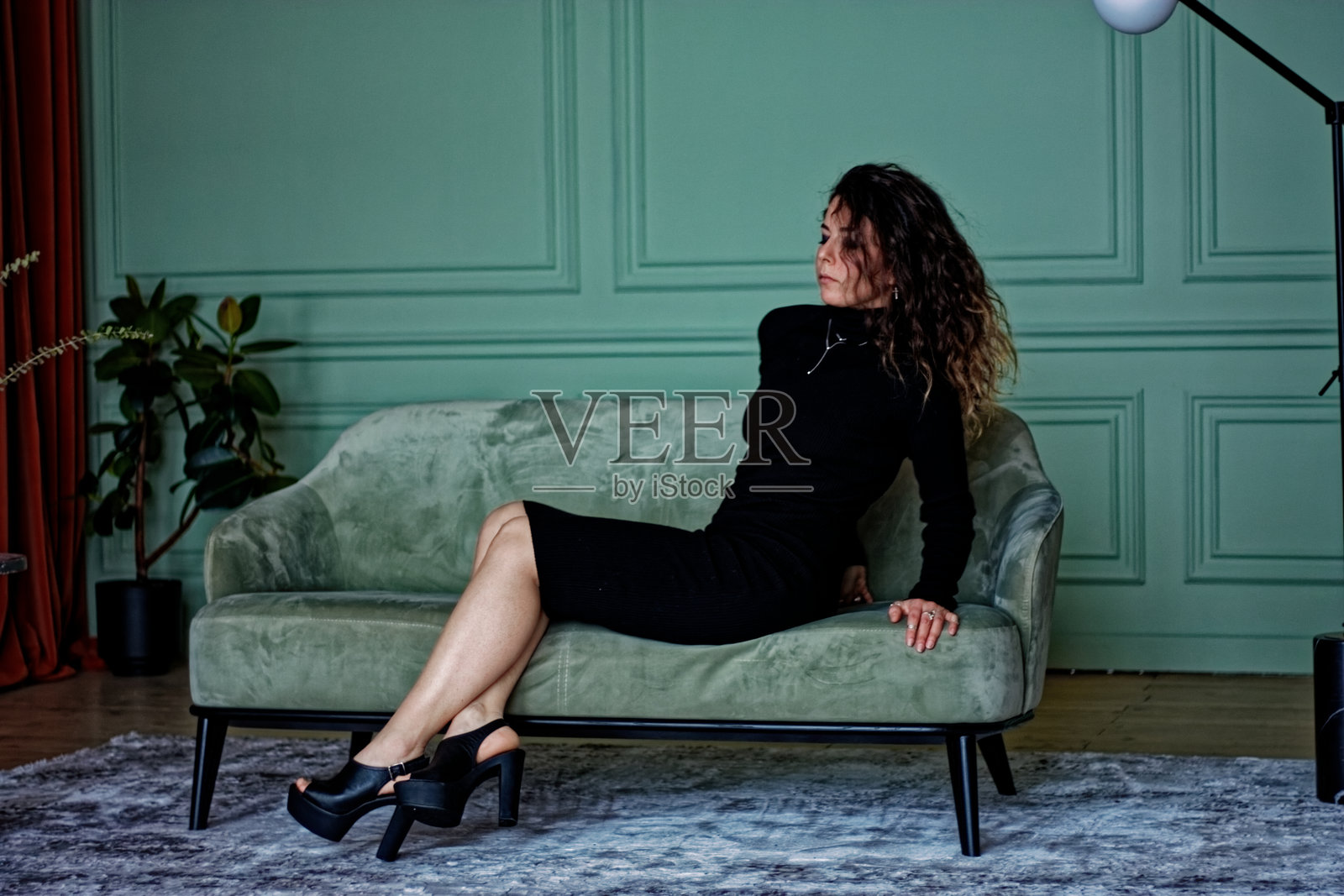 年轻女性坐在绿色沙发上照片摄影图片