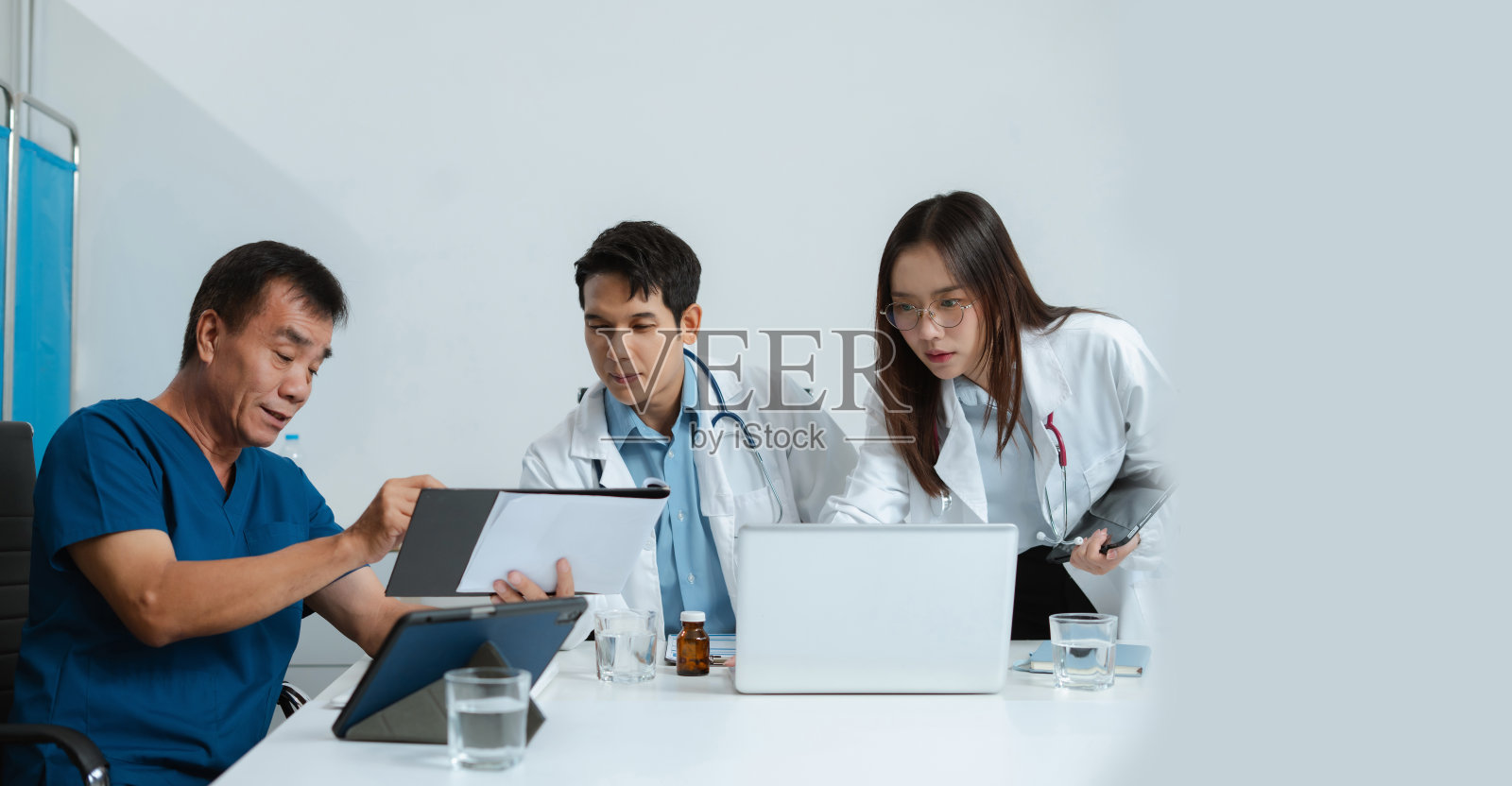 医疗团队在医院办公室使用数字平板电脑分析医疗报告的结果。照片摄影图片