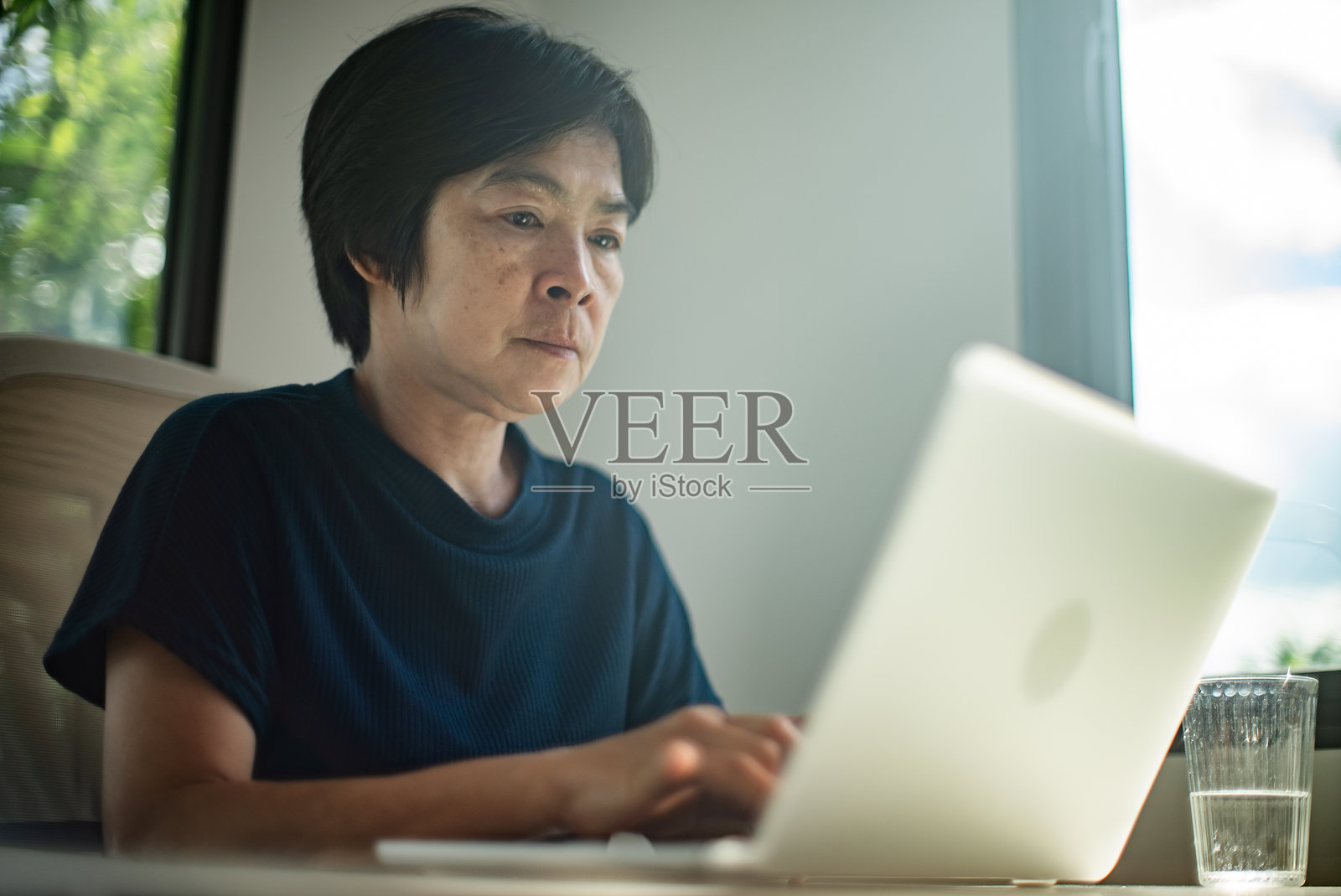 成熟的女性在使用笔记本电脑时感到炎热。照片摄影图片