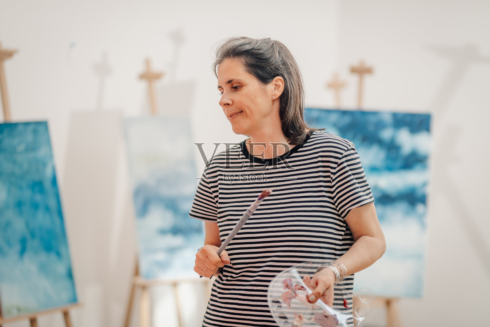 女性艺术家在艺术工作室中手持画笔和调色板照片摄影图片