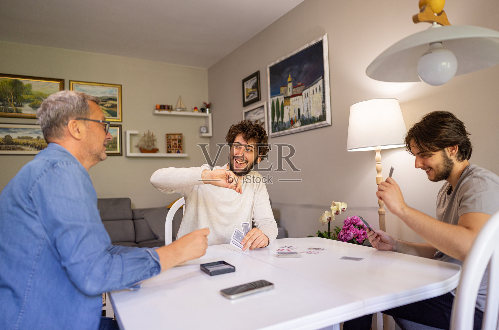 成熟男人在客厅与两个成年儿子玩牌照片摄影图片