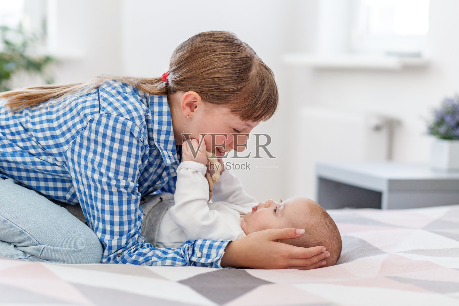 姐姐在温柔地和婴儿弟妹玩耍照片摄影图片
