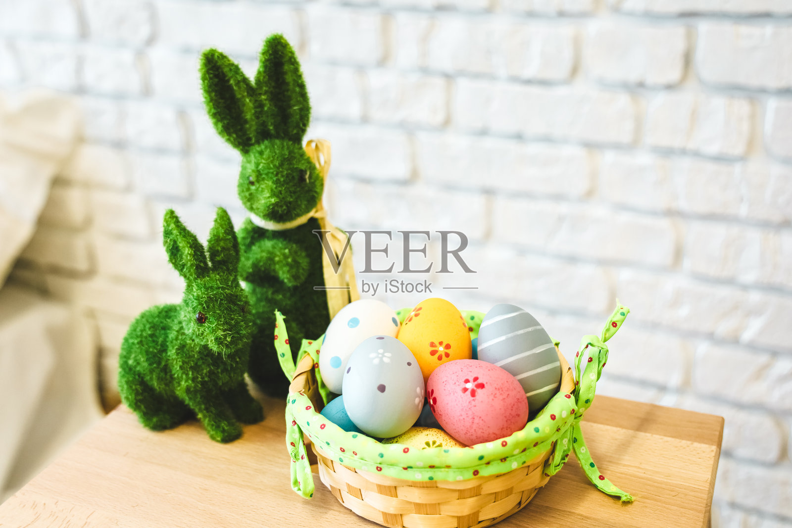 五彩缤纷的复活节彩蛋放在篮子里，旁边有装饰性的小兔子，摆放在木桌上照片摄影图片