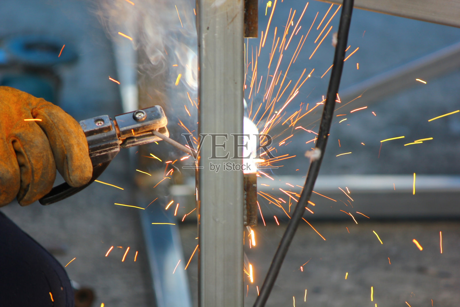 特写焊工在建筑工地焊接钢结构。焊工戴着皮手套和头盔，保护自己免受电击和高温。照片摄影图片