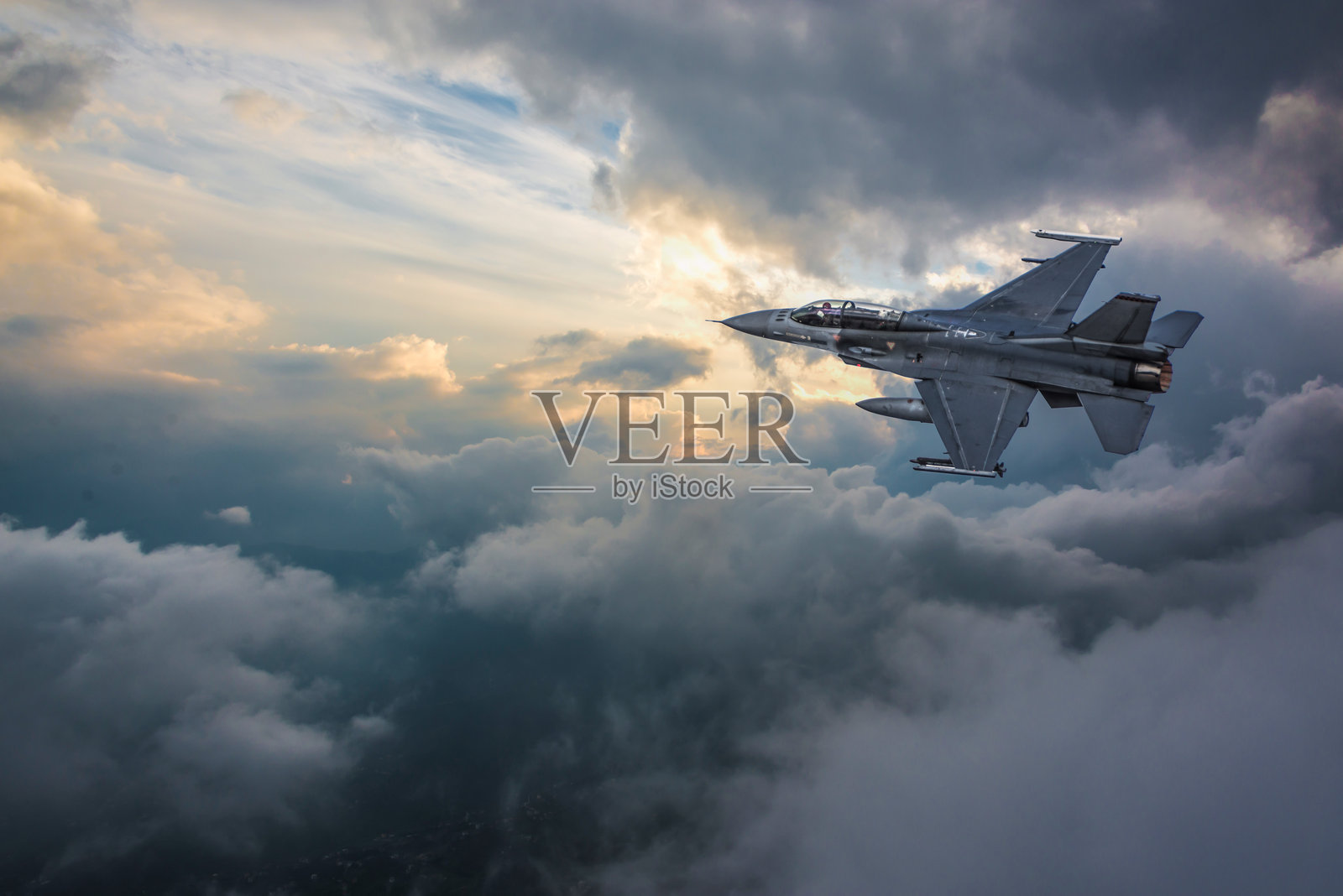 F-16战斗机在日落时分飞越云层照片摄影图片