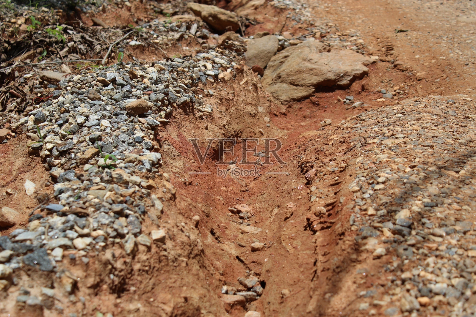 水流冲刷造成的土壤侵蚀特写，发生在碎石或砾石道路上。照片摄影图片