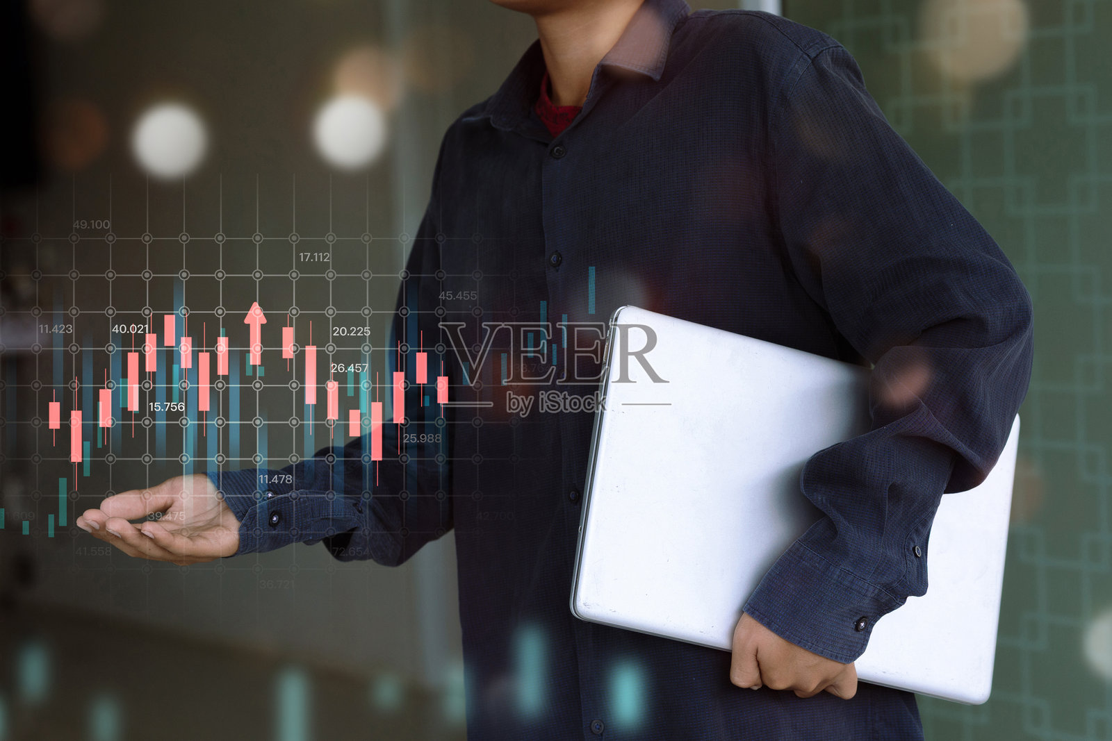 一位商人手持笔记本电脑，显示数字股票市场照片摄影图片